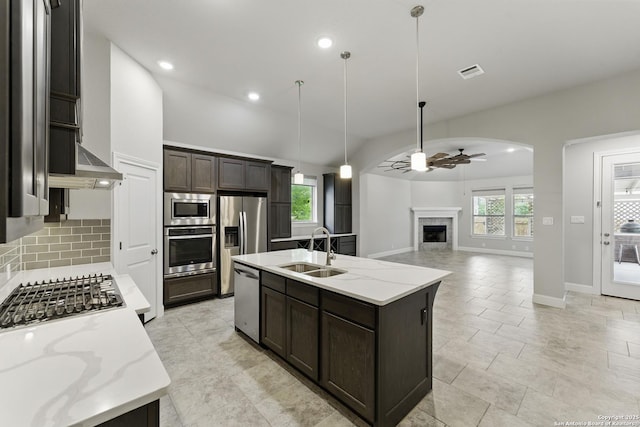 kitchen featuring dark brown cabinetry, appliances with stainless steel finishes, a sink, a ceiling fan, and decorative backsplash
