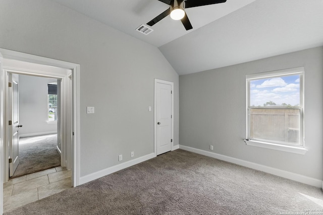 unfurnished bedroom with baseboards, vaulted ceiling, light carpet, and visible vents