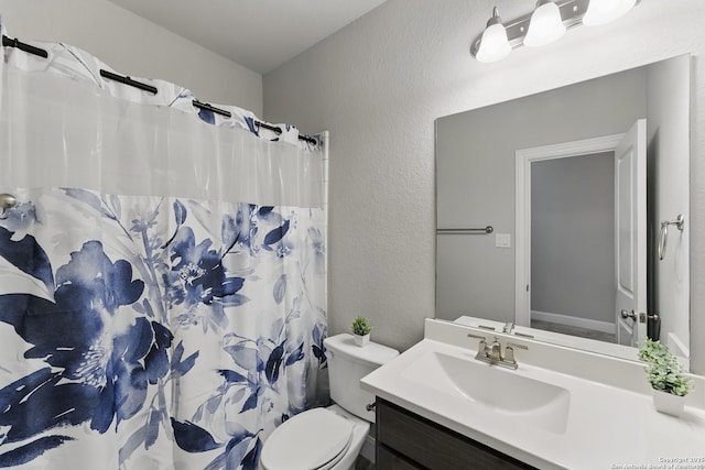 bathroom featuring vanity, a textured wall, a shower with curtain, and toilet