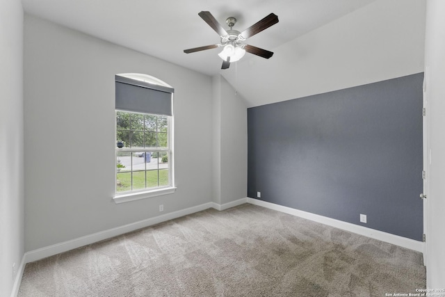 spare room with a ceiling fan, baseboards, vaulted ceiling, and carpet