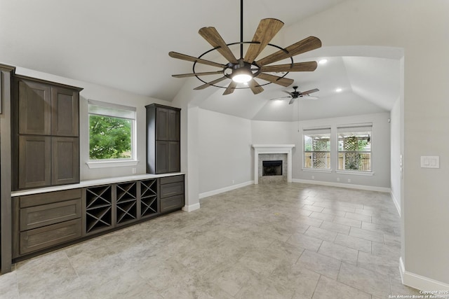 unfurnished living room with plenty of natural light, baseboards, ceiling fan, and lofted ceiling