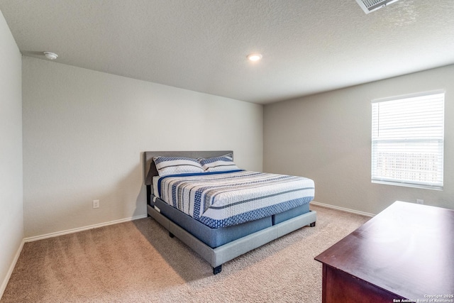 carpeted bedroom featuring a textured ceiling, baseboards, and visible vents