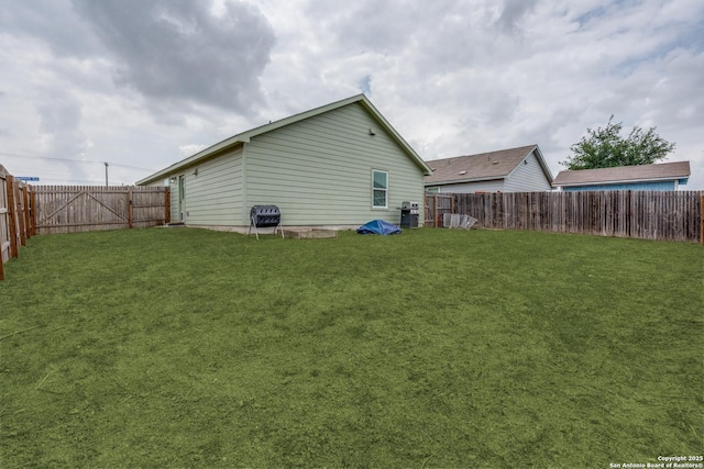 back of house with a fenced backyard and a yard