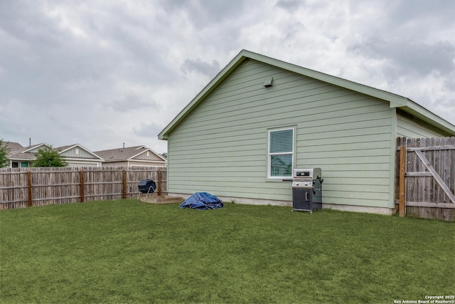 rear view of house with a lawn and a fenced backyard