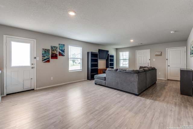living room featuring baseboards, recessed lighting, a textured ceiling, and wood finished floors