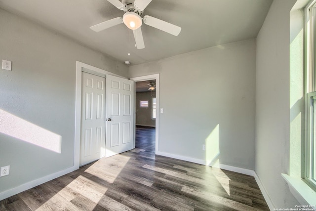 unfurnished bedroom featuring a closet, baseboards, ceiling fan, and wood finished floors