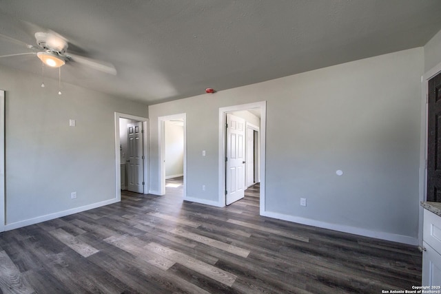 interior space with baseboards, a ceiling fan, and dark wood-style floors