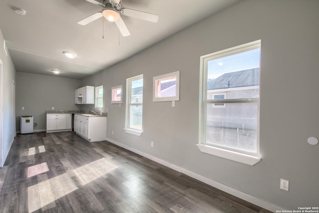interior space featuring white cabinetry, baseboards, dark wood finished floors, and a ceiling fan
