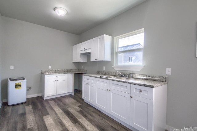kitchen with a sink, baseboards, white cabinets, dark wood-style floors, and under cabinet range hood