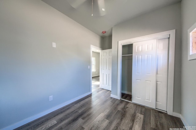 unfurnished bedroom featuring baseboards, a ceiling fan, dark wood finished floors, and a closet