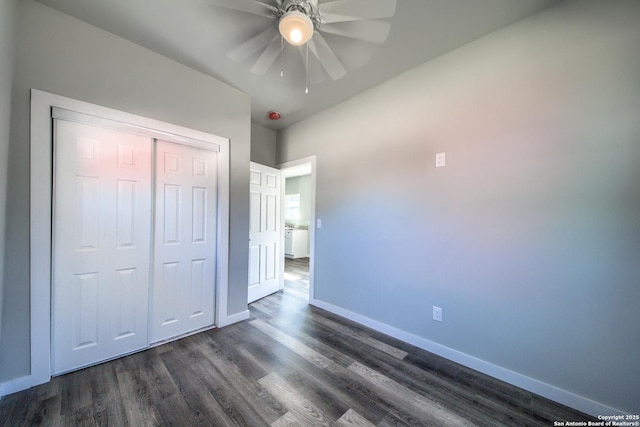 unfurnished bedroom featuring dark wood-style flooring, baseboards, a ceiling fan, and a closet