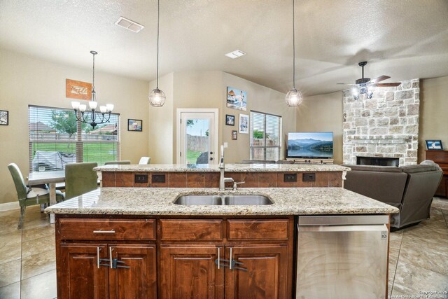 13139 Compass Rose, San Antonio, TX 78263 - kitchen featuring a sink, a stone fireplace, ceiling fan with notable chandelier, stainless steel dishwasher, and a center island with sink