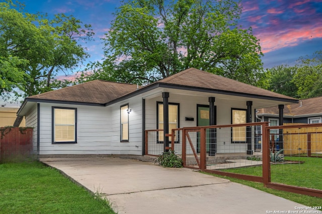 bungalow featuring a porch, a shingled roof, fence, and a yard