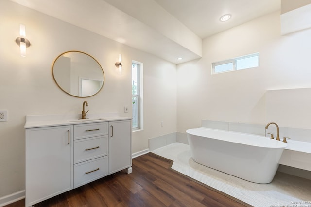 full bath featuring vanity, recessed lighting, wood finished floors, and a soaking tub