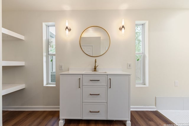 bathroom with baseboards, plenty of natural light, wood finished floors, and vanity