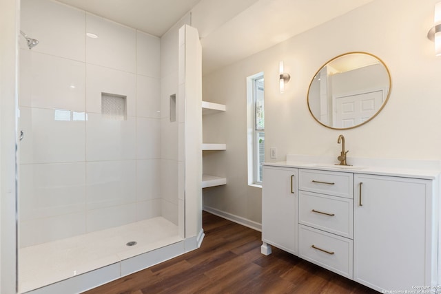 full bathroom featuring vanity, baseboards, a tile shower, and wood finished floors