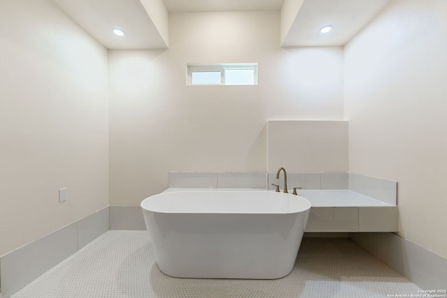 bathroom with recessed lighting, a freestanding tub, and tile patterned floors
