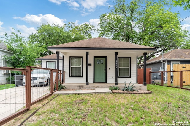 bungalow-style house featuring a porch, fence, a shingled roof, and a front lawn