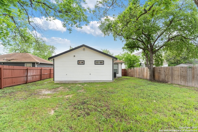 rear view of house featuring a fenced backyard and a yard