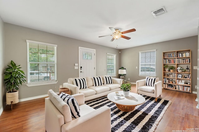 living area with visible vents, a ceiling fan, light wood finished floors, and plenty of natural light