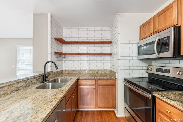 kitchen with open shelves, a sink, light wood-style flooring, stainless steel appliances, and backsplash