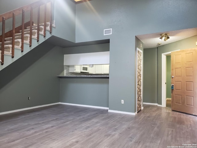 4107 Medical Unit 1204, San Antonio, TX 78229 - unfurnished living room with stairs, baseboards, visible vents, and wood finished floors