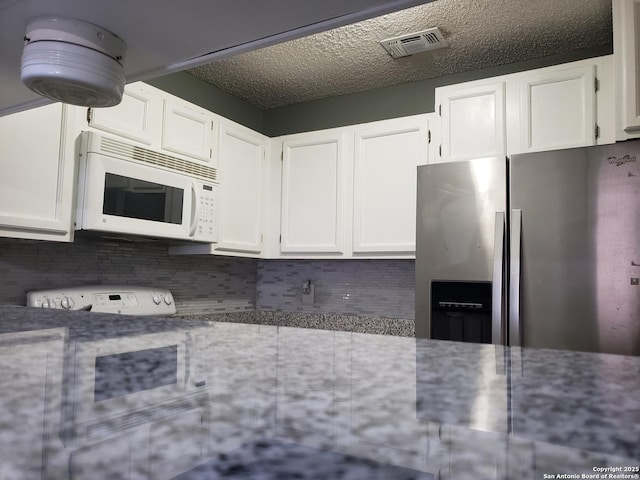 4107 Medical Unit 1204, San Antonio, TX 78229 - kitchen featuring light stone countertops, visible vents, stainless steel fridge with ice dispenser, and white microwave