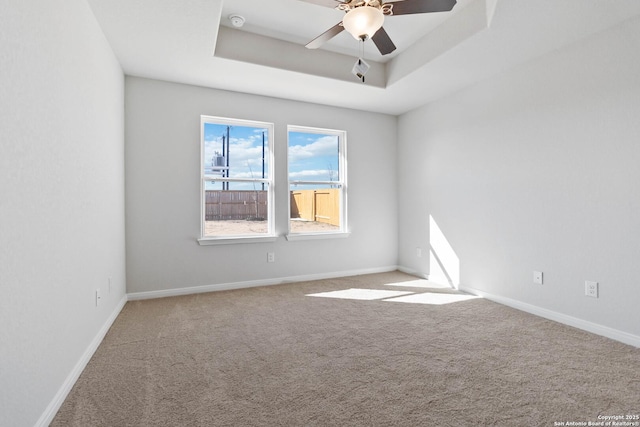 unfurnished room with baseboards, carpet, a raised ceiling, and a ceiling fan