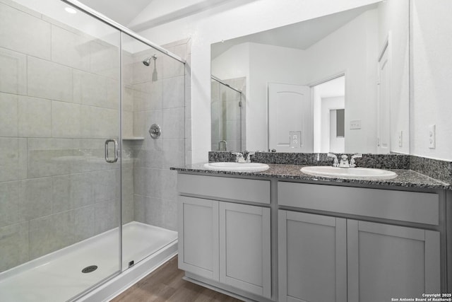 full bath with a sink, a stall shower, and double vanity