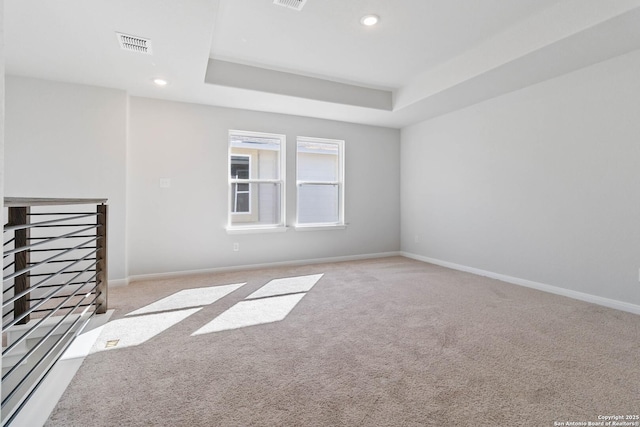 carpeted spare room featuring recessed lighting, baseboards, visible vents, and a raised ceiling