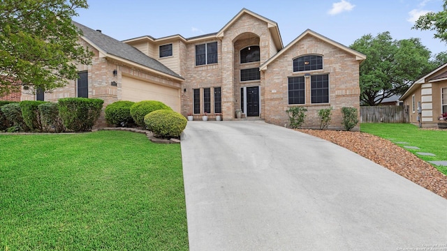 traditional home featuring fence, a front yard, brick siding, concrete driveway, and an attached garage