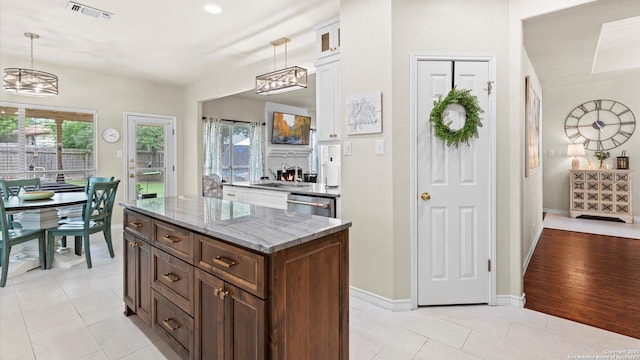 kitchen featuring light stone countertops, a sink, stainless steel dishwasher, visible vents, and pendant lighting