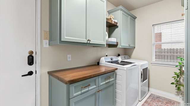 laundry room with separate washer and dryer, cabinet space, and baseboards