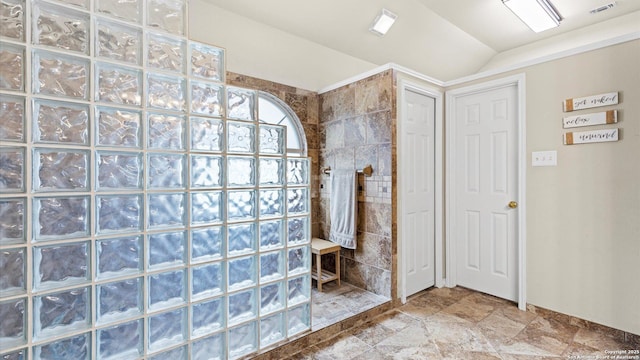 full bath with stone finish floor, visible vents, vaulted ceiling, a walk in shower, and baseboards