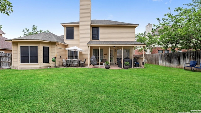 back of property featuring a yard, a patio, a chimney, and a fenced backyard