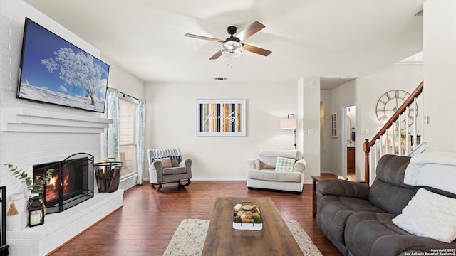 living room featuring ceiling fan, baseboards, wood finished floors, visible vents, and stairway