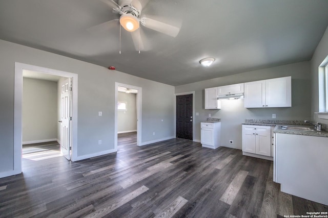 kitchen featuring dark wood-style flooring, baseboards, ceiling fan, white cabinetry, and under cabinet range hood
