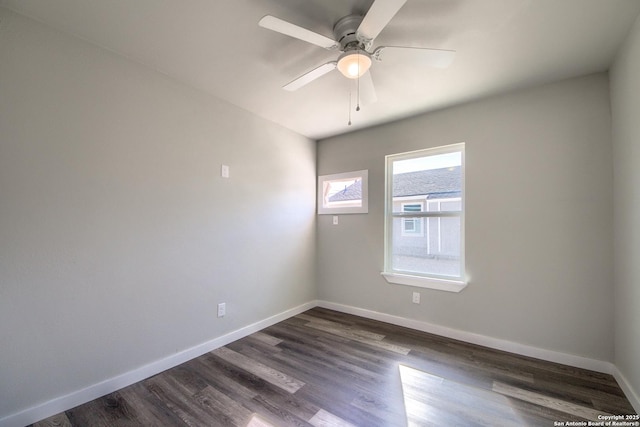 spare room with baseboards, dark wood-style flooring, and ceiling fan