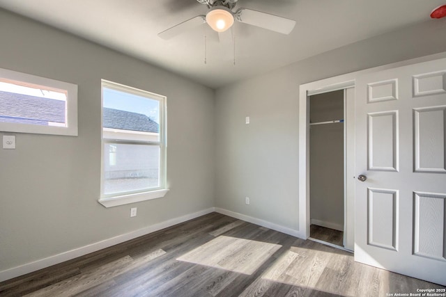 unfurnished bedroom featuring baseboards, ceiling fan, wood finished floors, and a closet