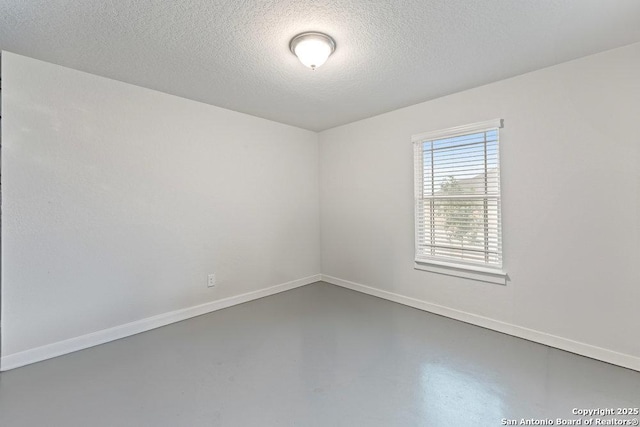 empty room featuring baseboards, a textured ceiling, and concrete flooring