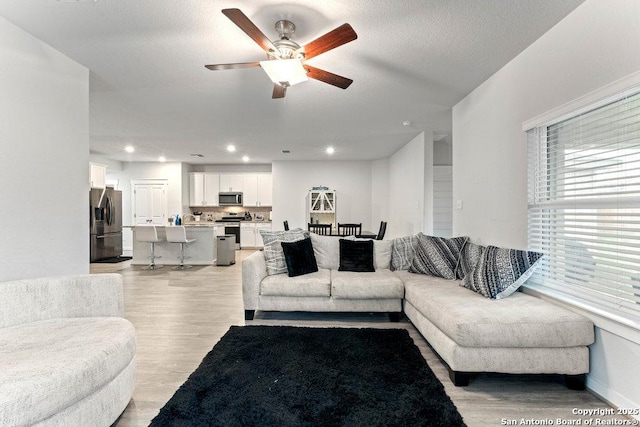 living room featuring recessed lighting, light wood finished floors, and ceiling fan