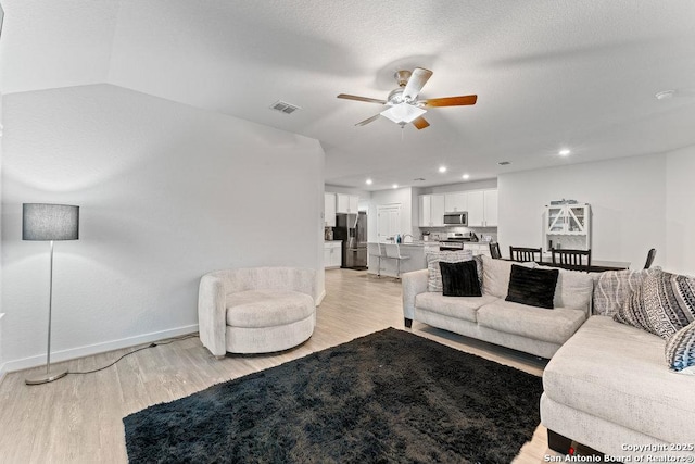 living area featuring ceiling fan, light wood finished floors, recessed lighting, baseboards, and visible vents