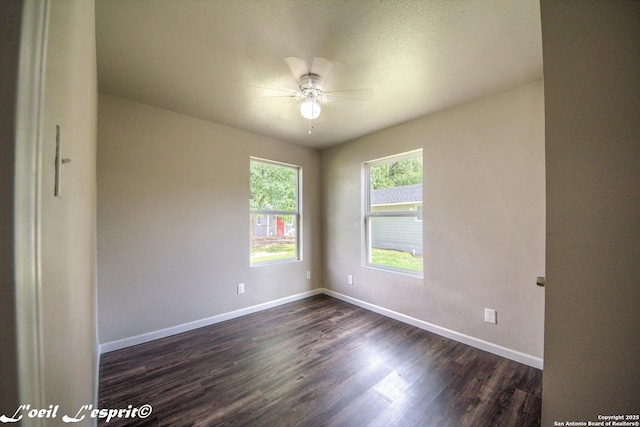 empty room featuring baseboards, ceiling fan, and dark wood finished floors