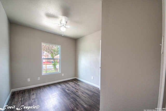 unfurnished room featuring dark wood-type flooring, a ceiling fan, and baseboards