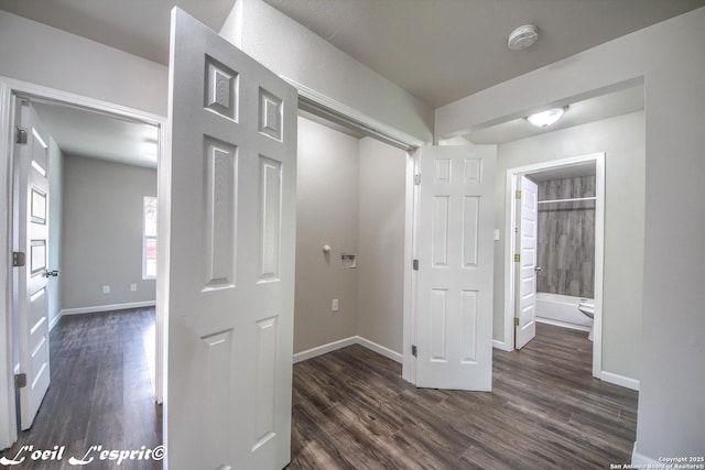 hallway featuring dark wood-style flooring and baseboards
