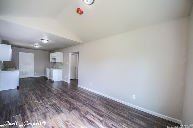 unfurnished living room with baseboards, vaulted ceiling, and dark wood-style floors