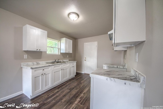 kitchen with baseboards, dark wood-style floors, light countertops, white cabinetry, and a sink