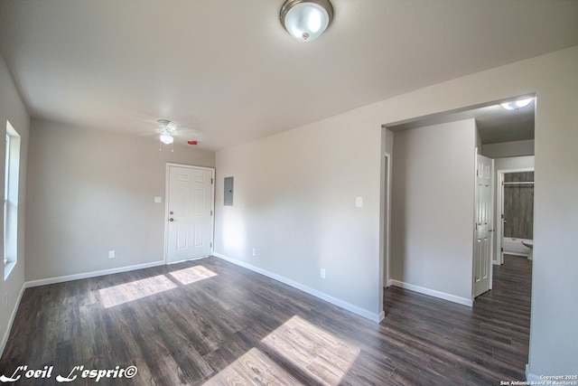 empty room featuring baseboards, electric panel, a ceiling fan, and dark wood finished floors