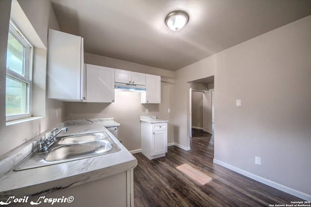 kitchen with light countertops, white cabinetry, dark wood-style floors, and a sink