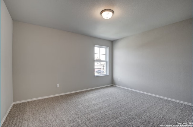 spare room featuring carpet floors and baseboards
